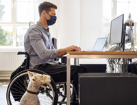 disabled man at computer with support dog